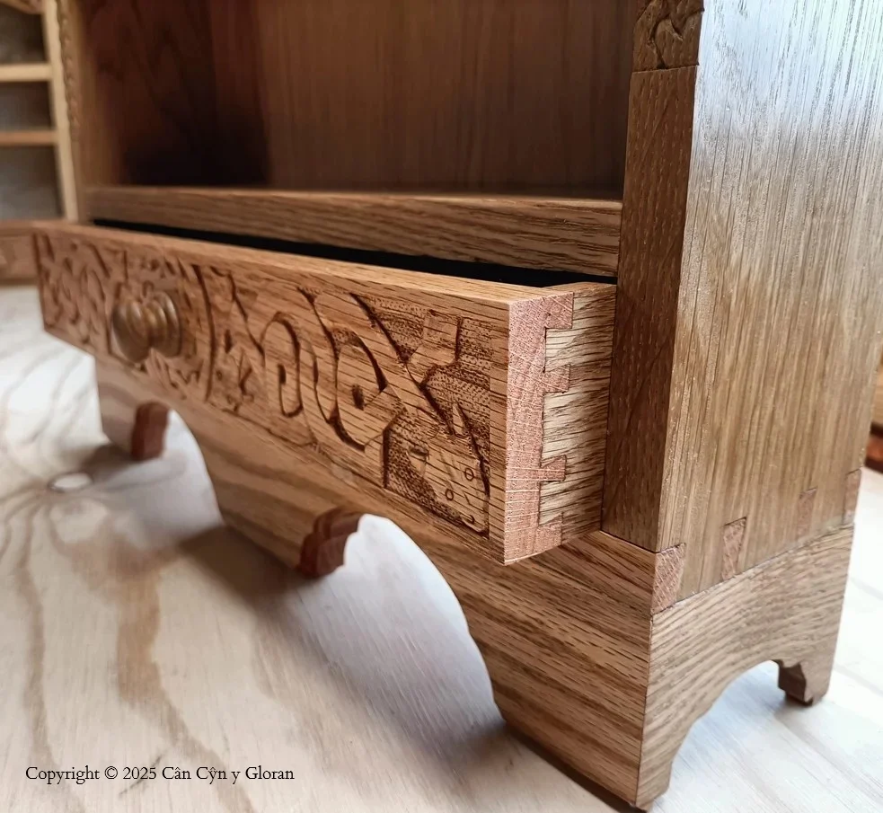 A hand carved oak cabinet, focusing on a drawer with half blind dovetails and Celtic dragons on the front, hand carved by a Welsh Gloran
